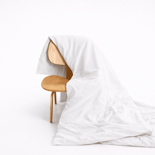 Funda nórdica de bambú blanco drapeada en silla de madera, mostrando textura suave y cierre con botones ocultos