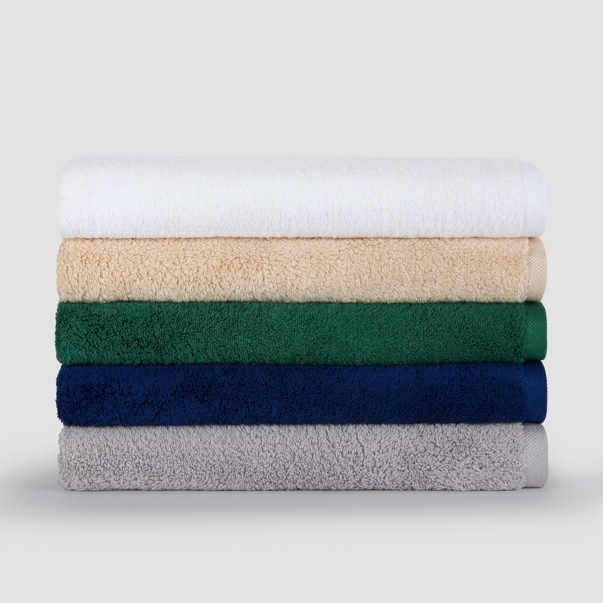 Stack of five folded bamboo towels in white, beige, green, navy, and gray colors displayed against a light background.