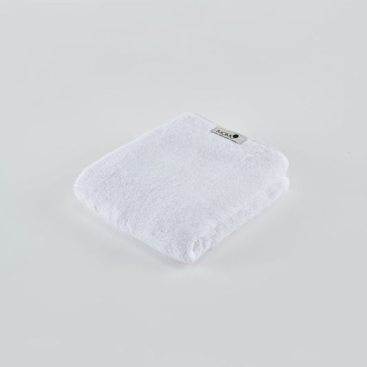 Toalla de bambú blanca Momo Cotton doblada en fondo claro con etiqueta de marca visible