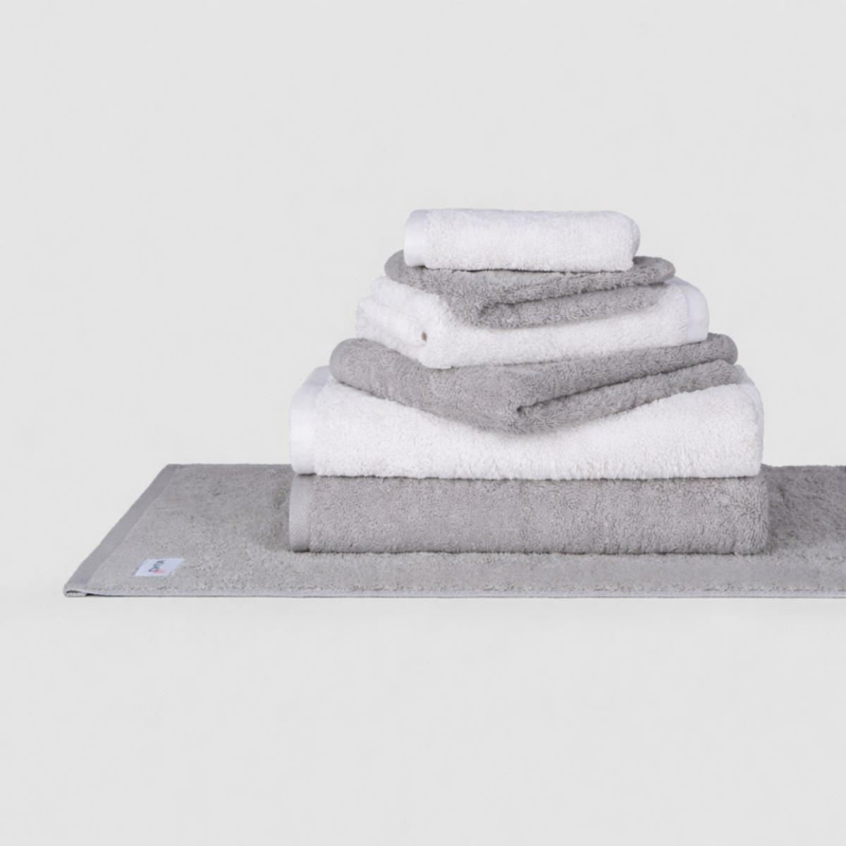 Conjunto de toallas Wabi Sabi de Momo Cotton en tonos gris y blanco apiladas sobre fondo blanco