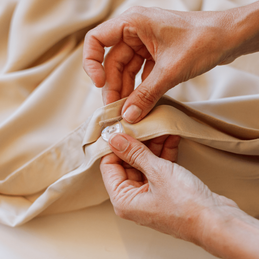 Manos tocando ropa de cama y toallas de algodón beige suave del conjunto de lino completo Momo Cotton