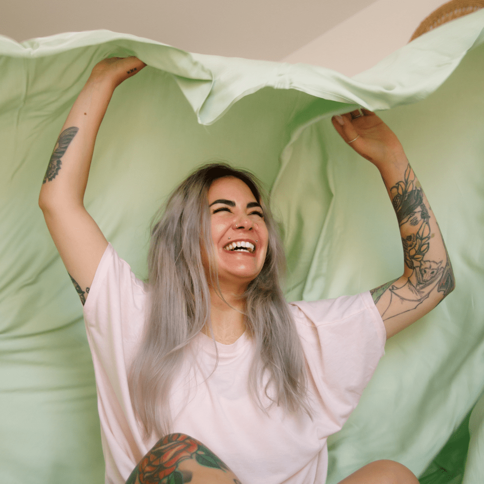 Mujer sonriente sosteniendo ropa de cama verde y blanca para noches de verano cómodas