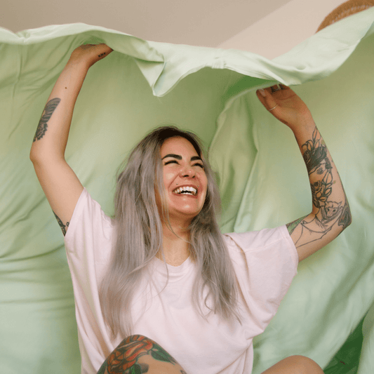 Mujer sonriente sosteniendo ropa de cama verde y blanca para noches de verano cómodas