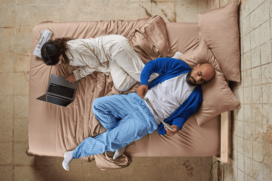 Pareja en la cama con sábanas de bambú durante el día, mostrando comodidad en diferentes estaciones.
