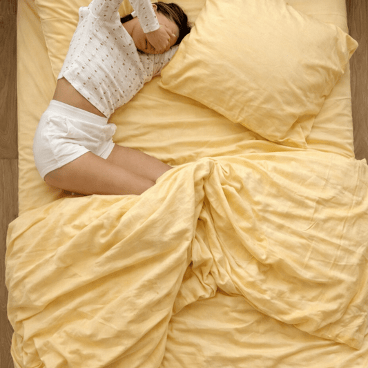 Cama con ropa de cama amarilla y almohada, persona acostada en posición de bedscaping decorativo.