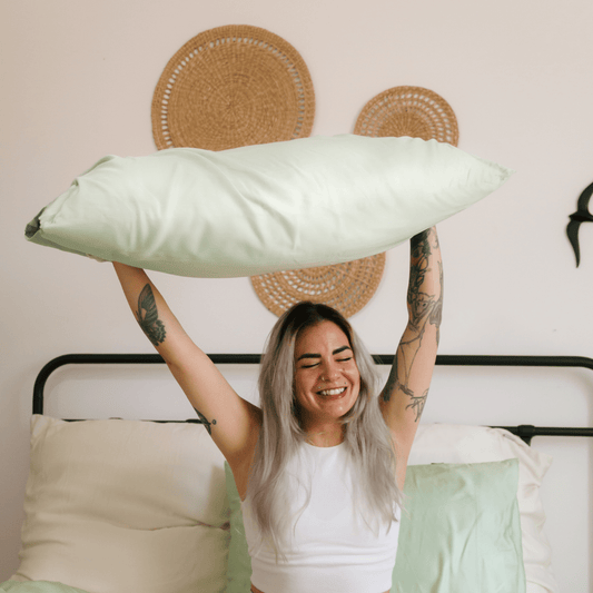 Mujer sosteniendo ropa de cama de bambú blanca y cómoda en una cama