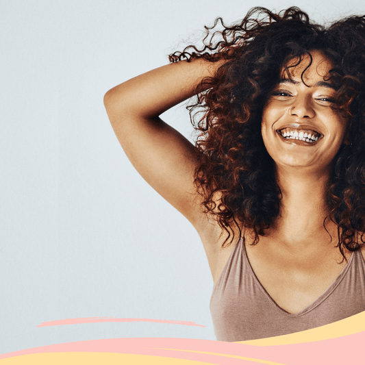 Mujer con cabello rizado castaño sonriendo, mostrando cabello hidratado y saludable.