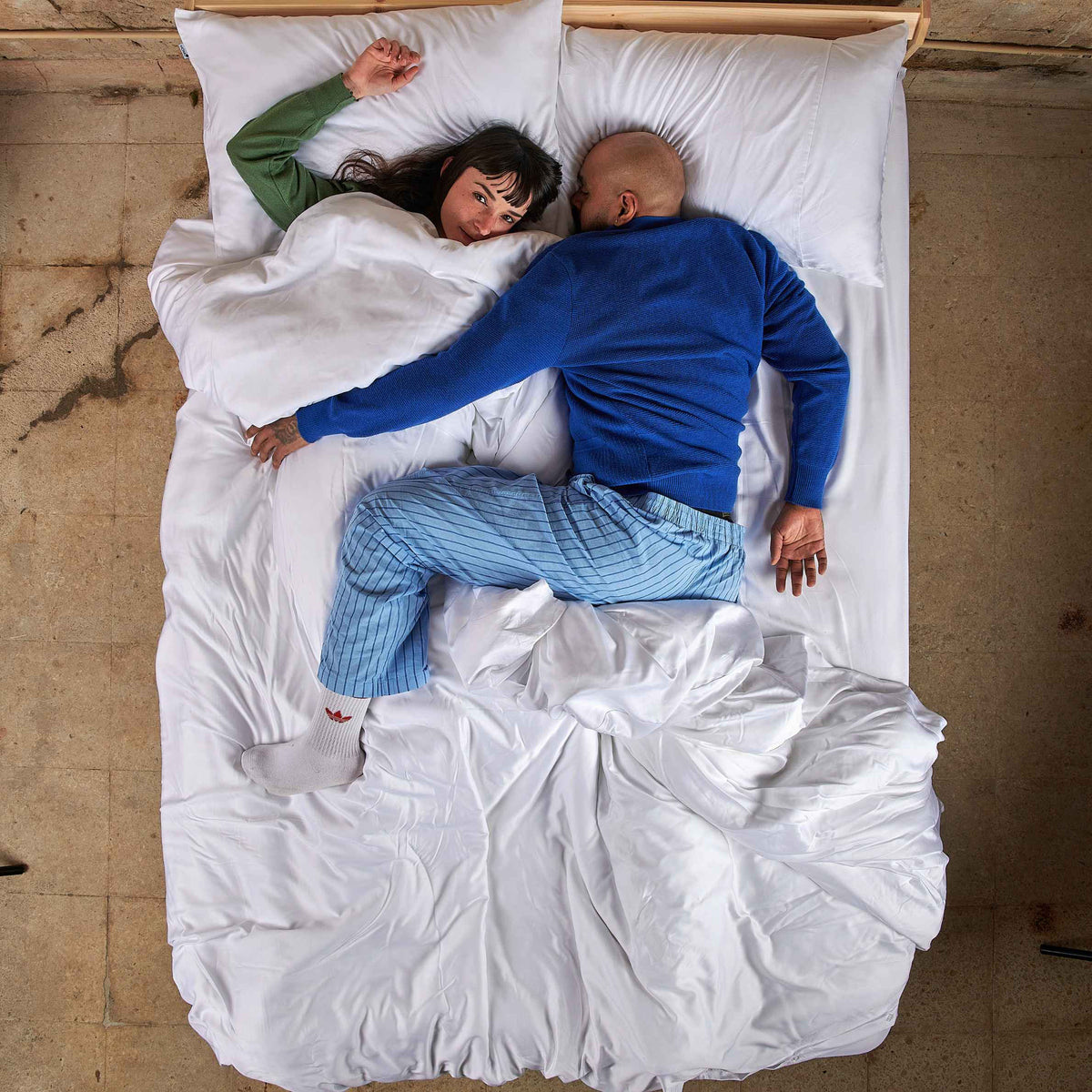 Pareja en la cama con juego de funda de edredón blanco de bambú, vista superior