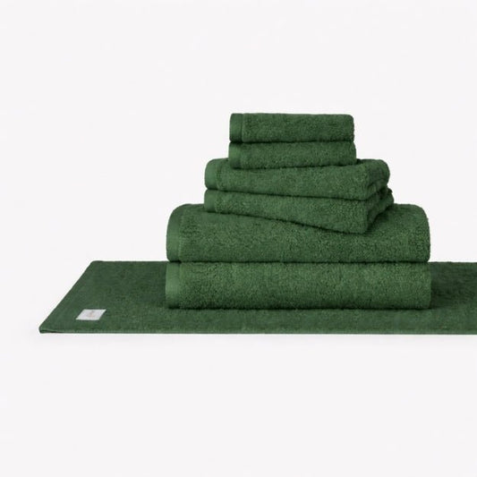 Juego de toallas de algodón Wabi Sabi verde apilado mostrando toallas de baño, toallas de mano y paños de cara en fondo blanco
