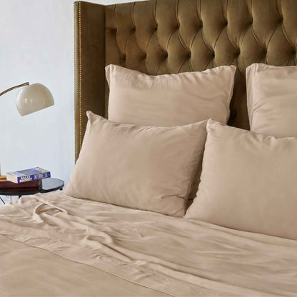 Cream top sheet on bed with brown upholstered headboard and beige pillows