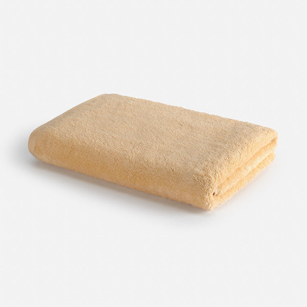 Beige Wabi-sabi bath towel folded on white background, 70x140cm by Momo Cotton