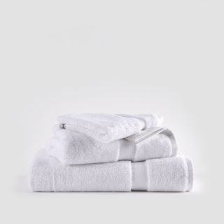 Juego de toallas de bambú blanco apiladas ordenadamente mostrando toallas faciales, de mano y baño con bandas texturadas.