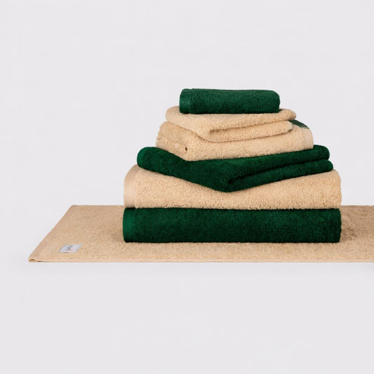Juego de toallas Momo Cotton Wabi Sabi apiladas en crema y verde bosque sobre fondo blanco