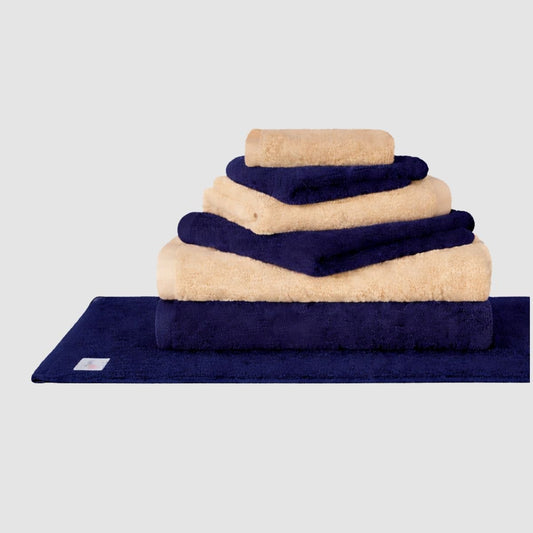 Juego de toallas Wabi Sabi en azul marino y beige apiladas sobre fondo gris
