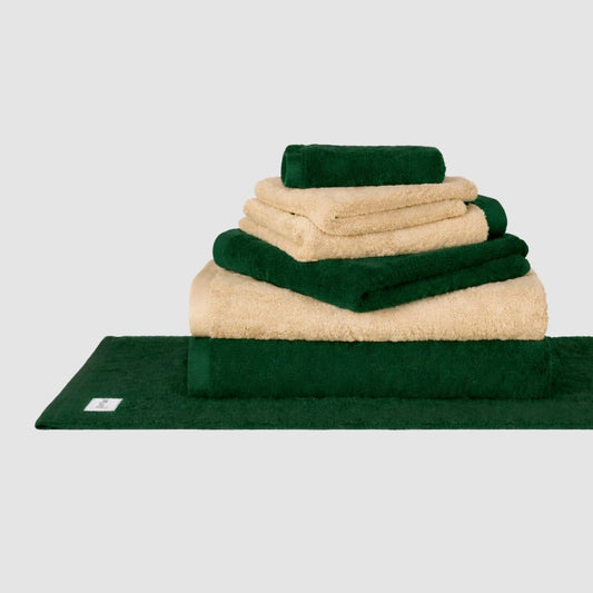 Juego de toallas Wabi Sabi verde y crema de Momo Cotton apiladas sobre fondo neutro