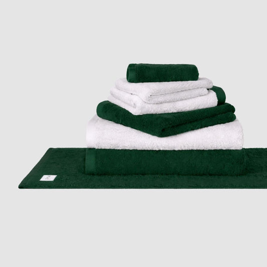 Conjunto de toallas Wabi Sabi en blanco y verde bosque apilado sobre fondo neutro