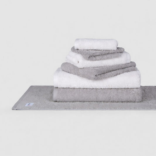 Conjunto de toallas Wabi Sabi de Momo Cotton en tonos gris y blanco apiladas sobre fondo blanco