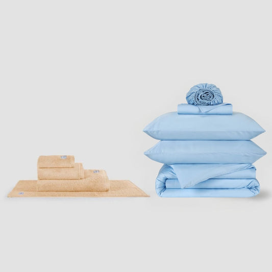 Juego de toallas beige y juego de sábanas azul apilados lado a lado, Momo Cotton