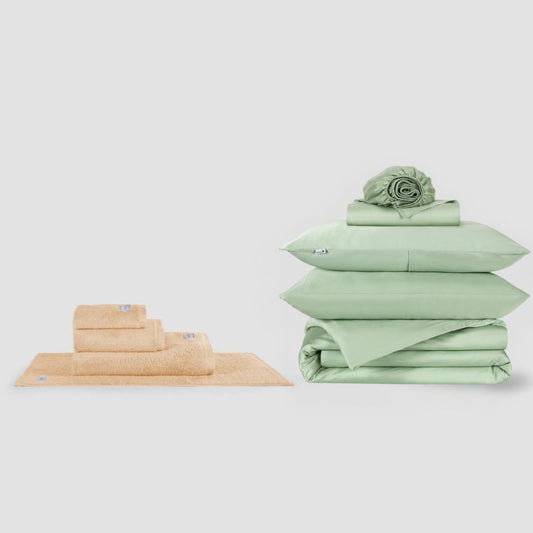 Set de toallas beige y sábanas verdes en paquete by Momo Cotton sobre fondo blanco
