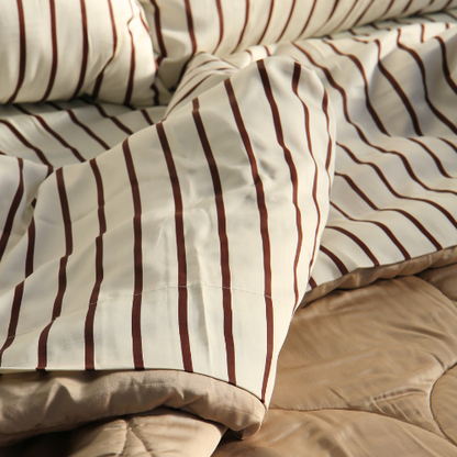 Sábana superior de bambú satinado con patrón de rayas marrones sobre cama con almohada beige