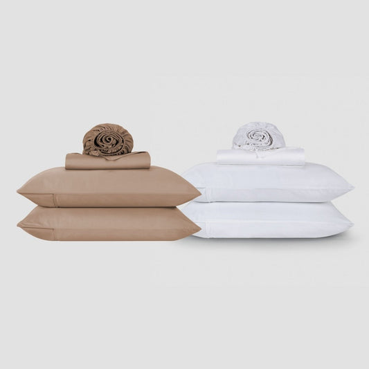 Juegos de sábanas de algodón beige y blanco apilados con ropa de cama enrollada y edredones sobre fondo neutro