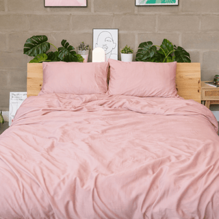 Vista frontal de un juego de cama de bambú rosa con textura naturalmente relajada en una habitación luminosa.