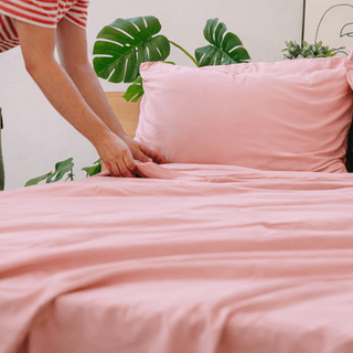 Manos sosteniendo tela de bambú rosa, destacando su textura ligera y sedosa.