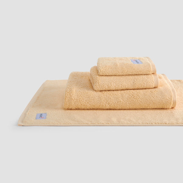 Conjunto de toallas de bambú beige Wabi-sabi apiladas, con toallas de cara, mano y baño con marca