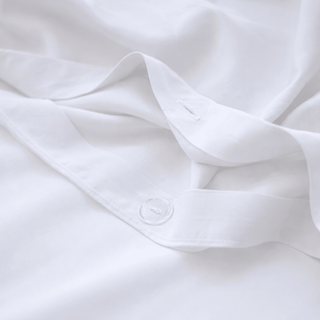 Juego de ropa de cama de algodón bambú blanco con detalle de botón visible en sábana doblada